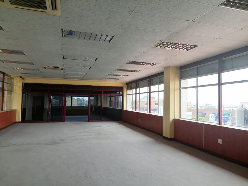 Spacious open-plan commercial office space featuring large windows, suspended ceilings with recessed lighting, and neutral wall paneling, ready for custom fit-out.
