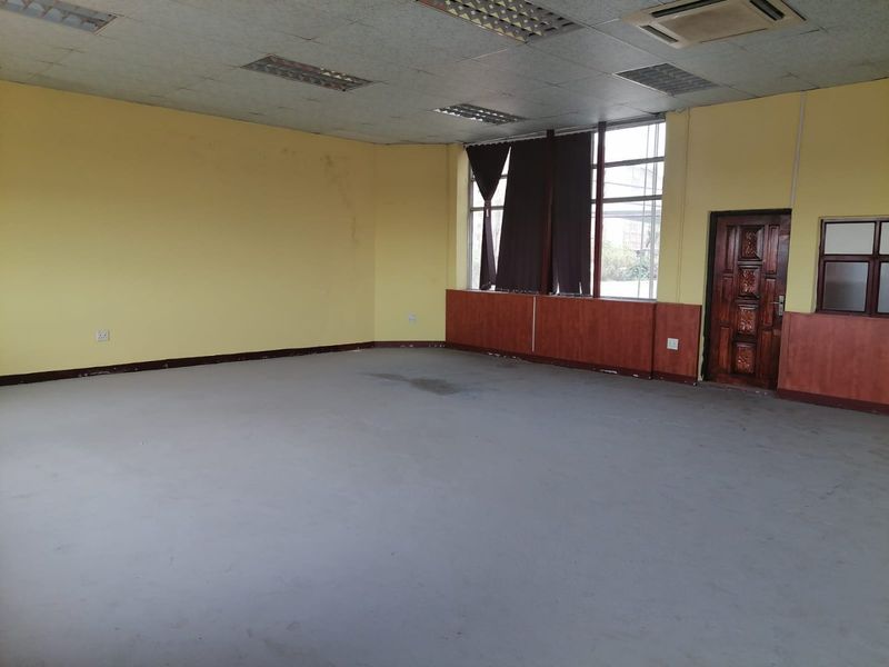 An empty commercial office space featuring a suspended ceiling, recessed lighting, air conditioning, and timber wall paneling.