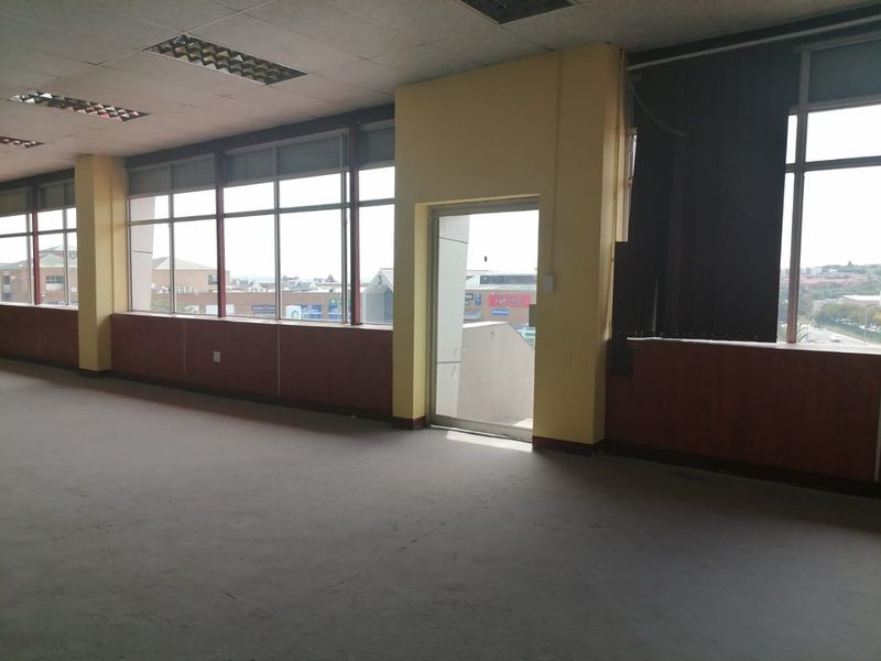 An empty, open-plan commercial office space featuring large windows, suspended ceilings, and a glass door, offering potential for custom fit-out and renovation.