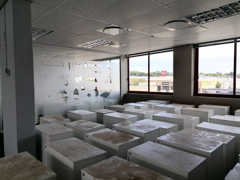 Open-plan commercial office space featuring a suspended ceiling, recessed lighting, and a frosted glass partition with views of the surrounding area.
