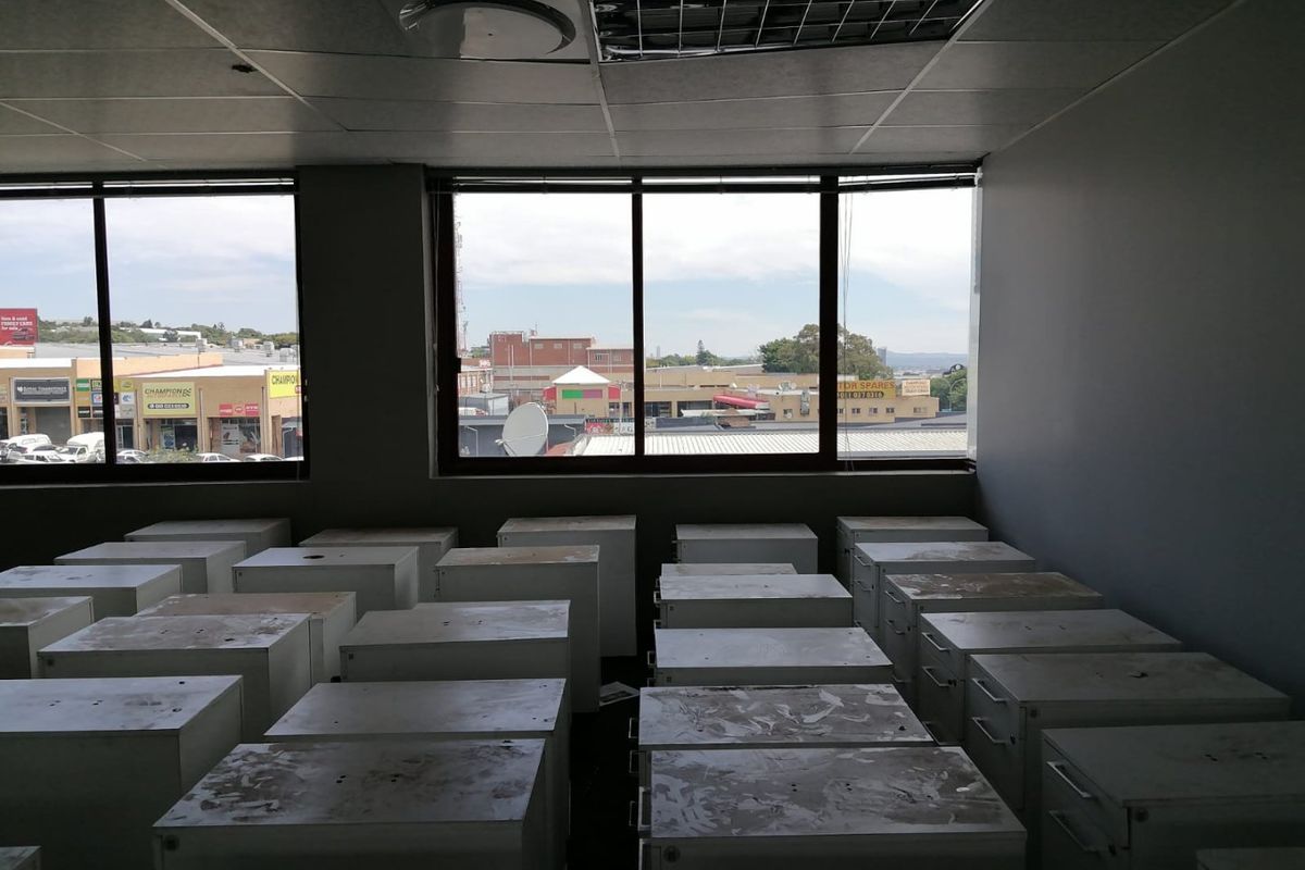 An empty commercial office space featuring large windows with street views, a suspended ceiling, and recessed lighting, suitable for various business configurations.