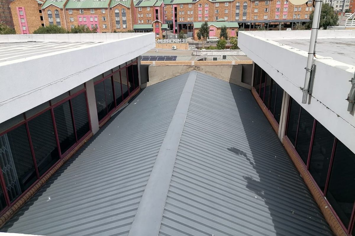 Aerial view of a commercial building featuring a pitched corrugated metal roof and surrounding aluminum-framed windows with security bars.
