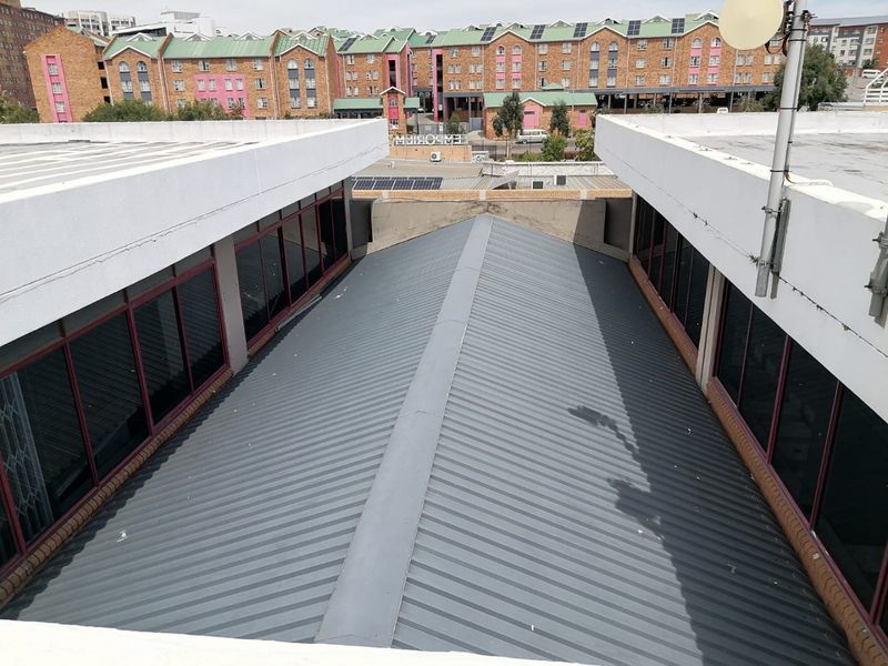 Aerial view of a commercial building featuring a pitched corrugated metal roof and surrounding aluminum-framed windows with security bars.