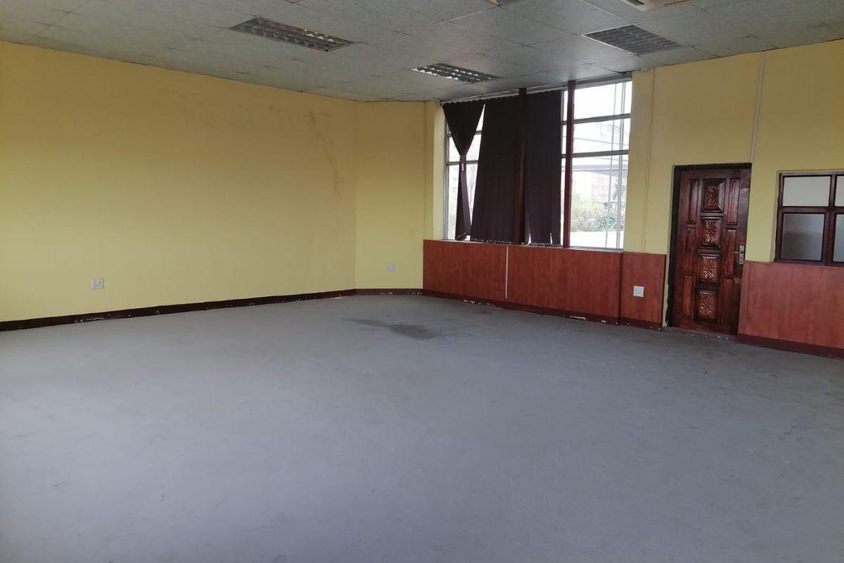 An empty commercial office space featuring a suspended ceiling, recessed lighting, air conditioning, and timber wall paneling.