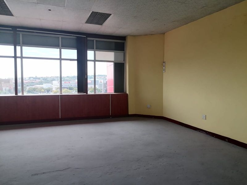 An empty commercial office space featuring large windows with city views, suspended ceiling, and carpet flooring, ready for custom fit-out.