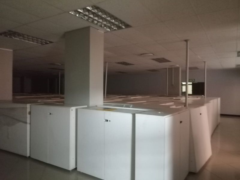 Commercial office space featuring a suspended ceiling, recessed lighting, tiled flooring, and extensive built-in storage cabinetry throughout the open-plan area.