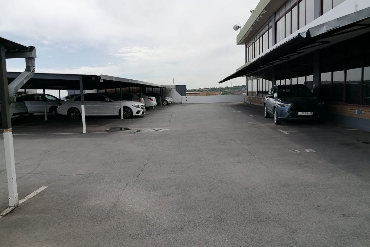 Commercial property exterior featuring a paved parking area with covered bays and direct access to the building facade.