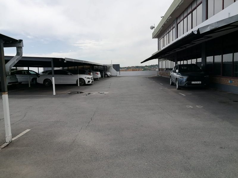 Commercial property exterior featuring a paved parking area with covered bays and direct access to the building facade.