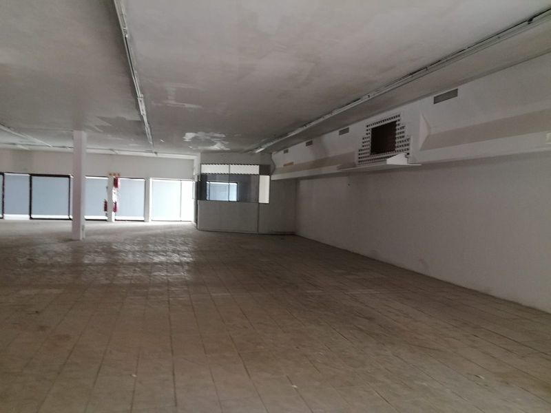 Spacious open-plan commercial interior featuring tiled flooring, a glass-partitioned office area, and suspended ceiling, currently vacant and ready for renovation.