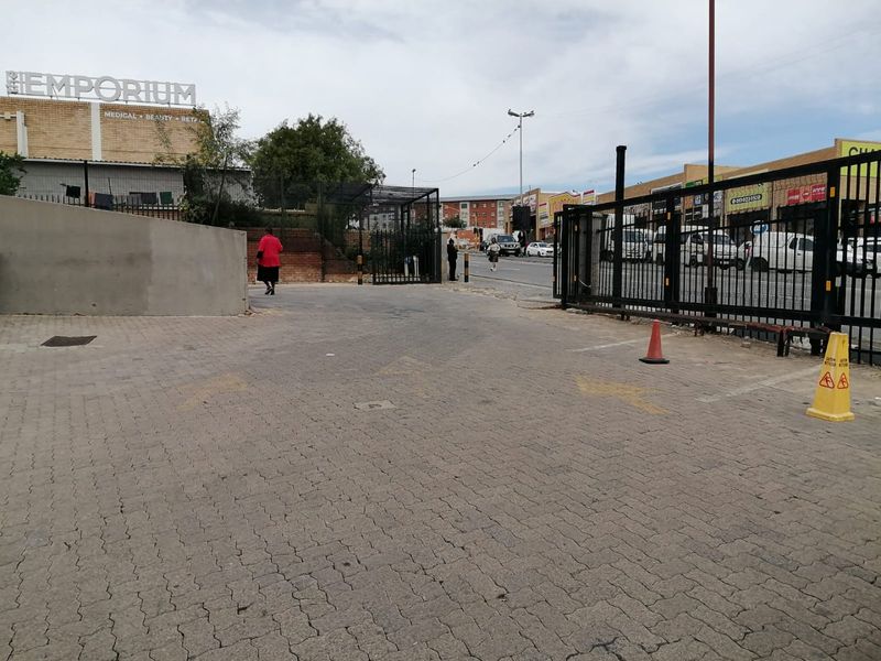 Exterior view of a commercial property entrance featuring a paved driveway, metal security gate, and perimeter fencing.