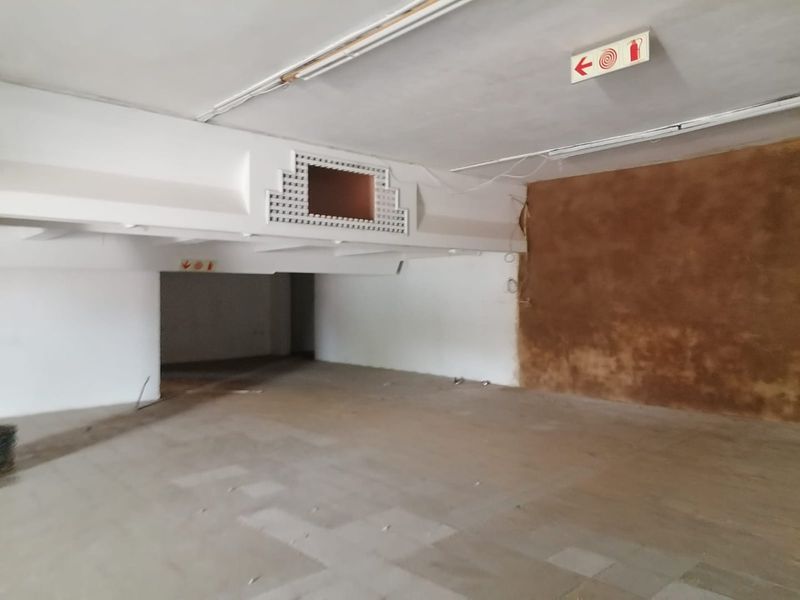 An expansive, vacant commercial open-plan space featuring exposed ceiling elements, fire safety signage, and unfinished wall finishes, suitable for custom fit-out.