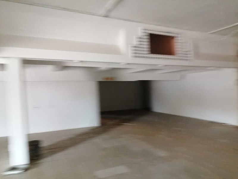 An empty, unfinished commercial interior space featuring exposed structural beams and ventilation ducting, requiring significant renovation and finishing work.