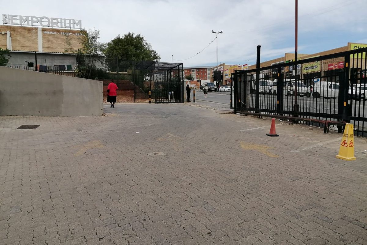 Exterior view of a commercial property entrance featuring a paved driveway, metal security gate, and perimeter fencing.