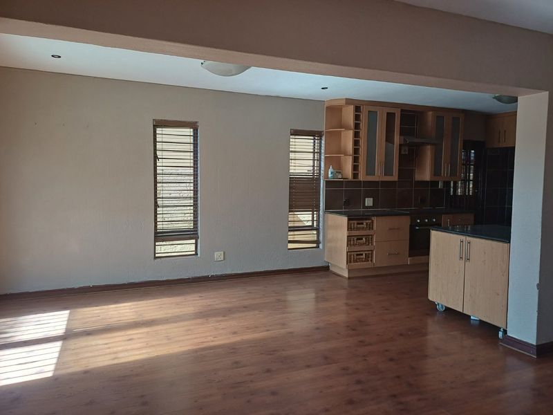 Open-plan living area featuring laminate flooring and a functional kitchen with built-in cabinetry, integrated oven, and extractor fan.