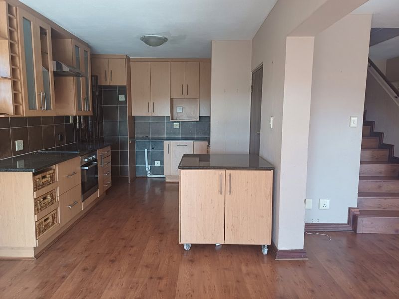 Kitchen featuring light wood cabinetry, granite countertops, built-in oven, and extractor fan, adjacent to a staircase with laminate flooring throughout.