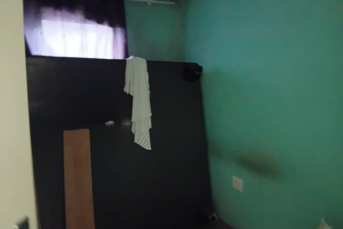 A small, vacant bedroom featuring green walls with visible signs of wear and staining, requiring cosmetic updates.