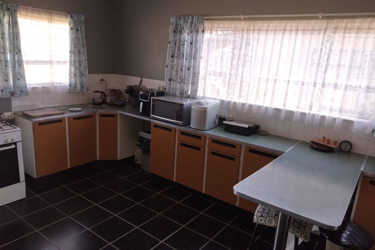 A functional kitchen featuring dark tiled flooring, laminate cabinetry, and a breakfast bar, offering a dated but well-maintained layout ready for modernization.