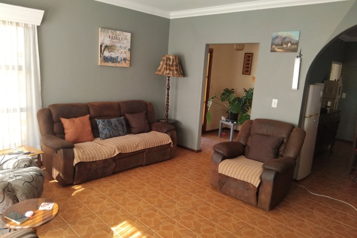 A living room featuring ceramic tile flooring, coved ceiling cornices, and an arched doorway leading to an adjacent space.