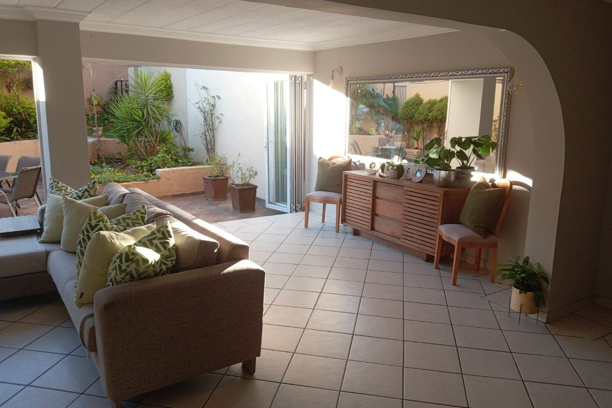 Spacious living area featuring tiled flooring and large bi-fold doors that open onto a private patio and garden space.