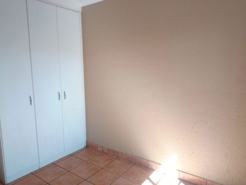 An empty bedroom featuring tiled flooring and built-in cupboards, offering a blank canvas for personalization.