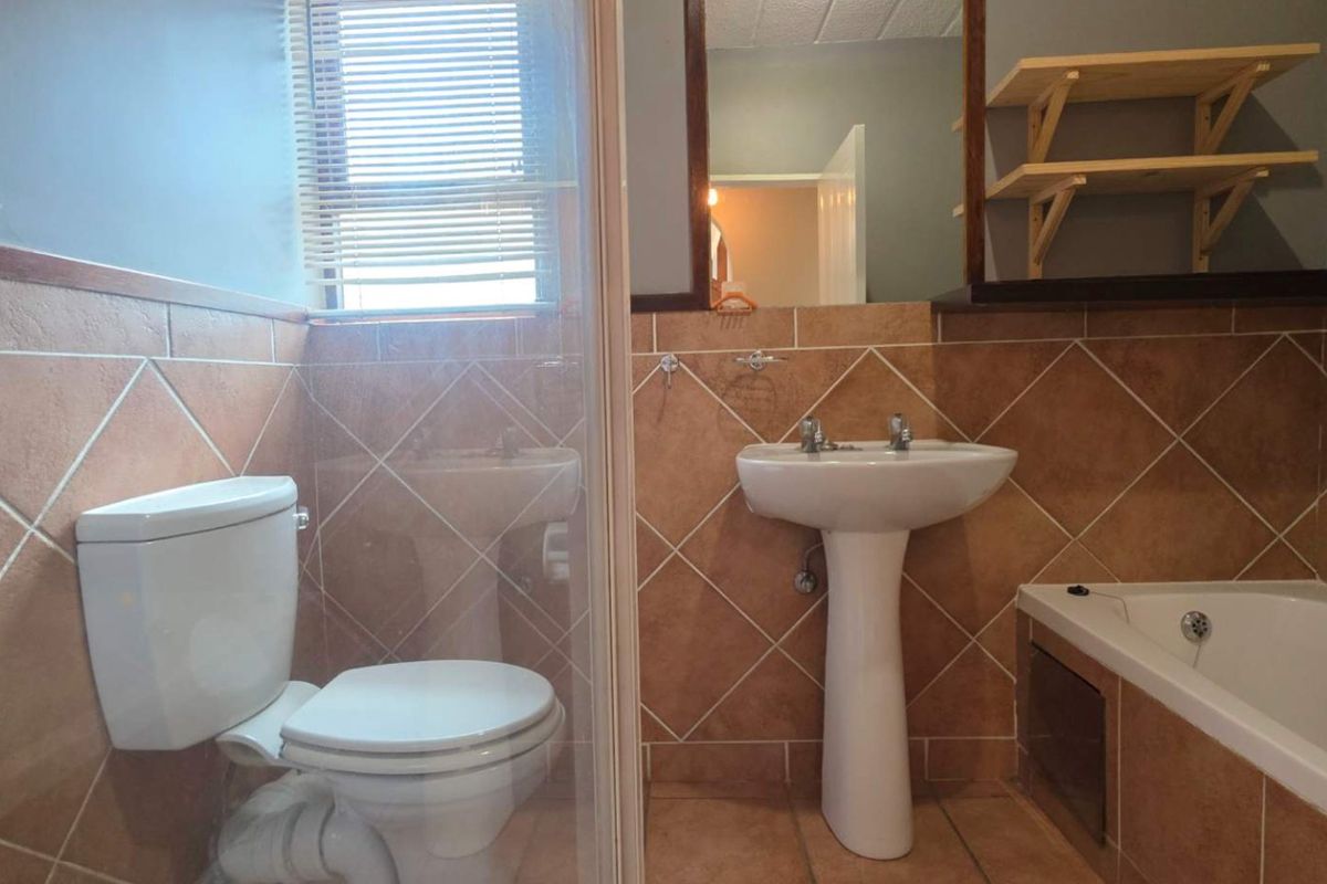 A functional bathroom featuring a pedestal basin, bathtub, and separate shower enclosure with tiled finishes throughout.