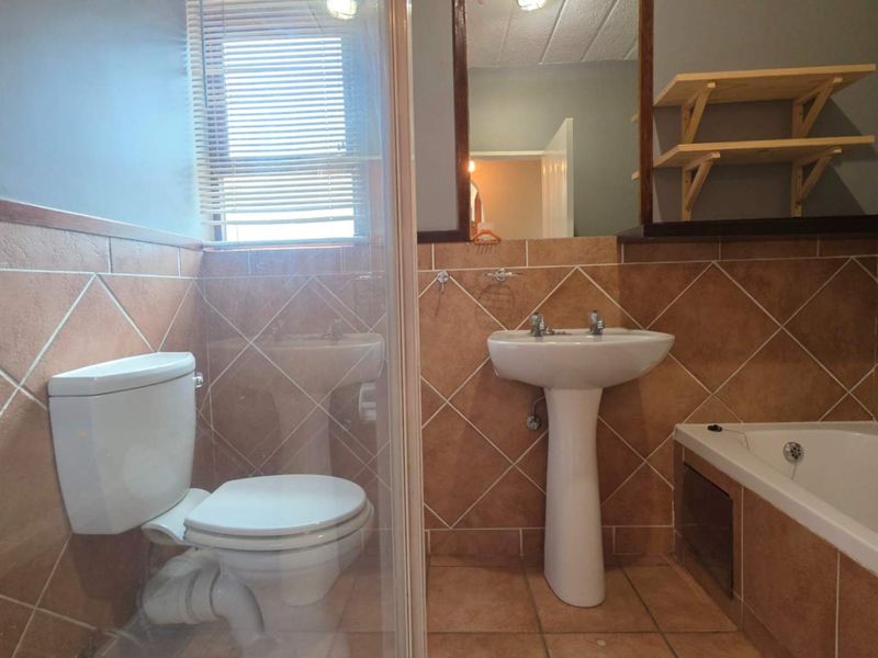 A functional bathroom featuring a pedestal basin, bathtub, and separate shower enclosure with tiled finishes throughout.