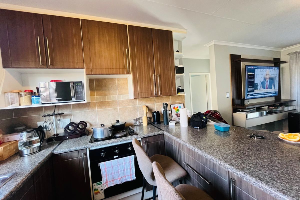 Open-plan kitchen featuring dark wood cabinetry, granite countertops, and a breakfast bar, seamlessly flowing into the adjacent living area.