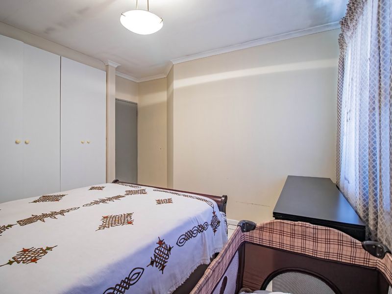 A functional bedroom featuring built-in cupboards and neutral wall finishes, providing a practical space with potential for modern updates.