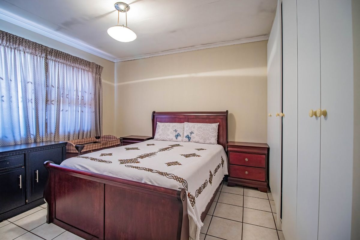 A bedroom featuring tiled flooring and built-in cupboards, showing visible signs of ceiling water damage requiring maintenance.