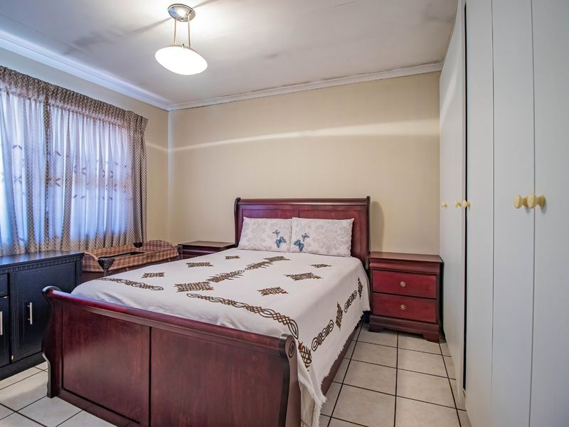 A bedroom featuring tiled flooring and built-in cupboards, showing visible signs of ceiling water damage requiring maintenance.