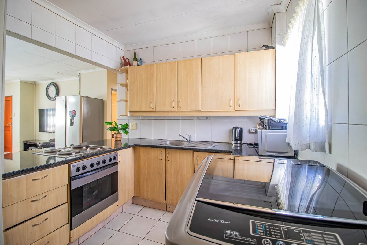 Functional kitchen featuring light wood cabinetry, granite countertops, integrated oven and hob, and tiled backsplash, offering a practical layout for daily meal preparation.