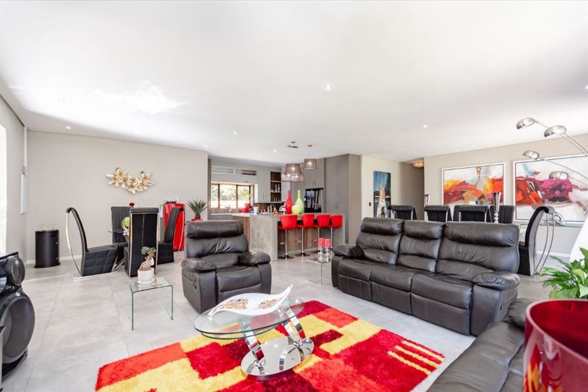 Spacious open-plan living and dining area featuring a modern kitchen island, neutral tiled flooring, and recessed lighting throughout.