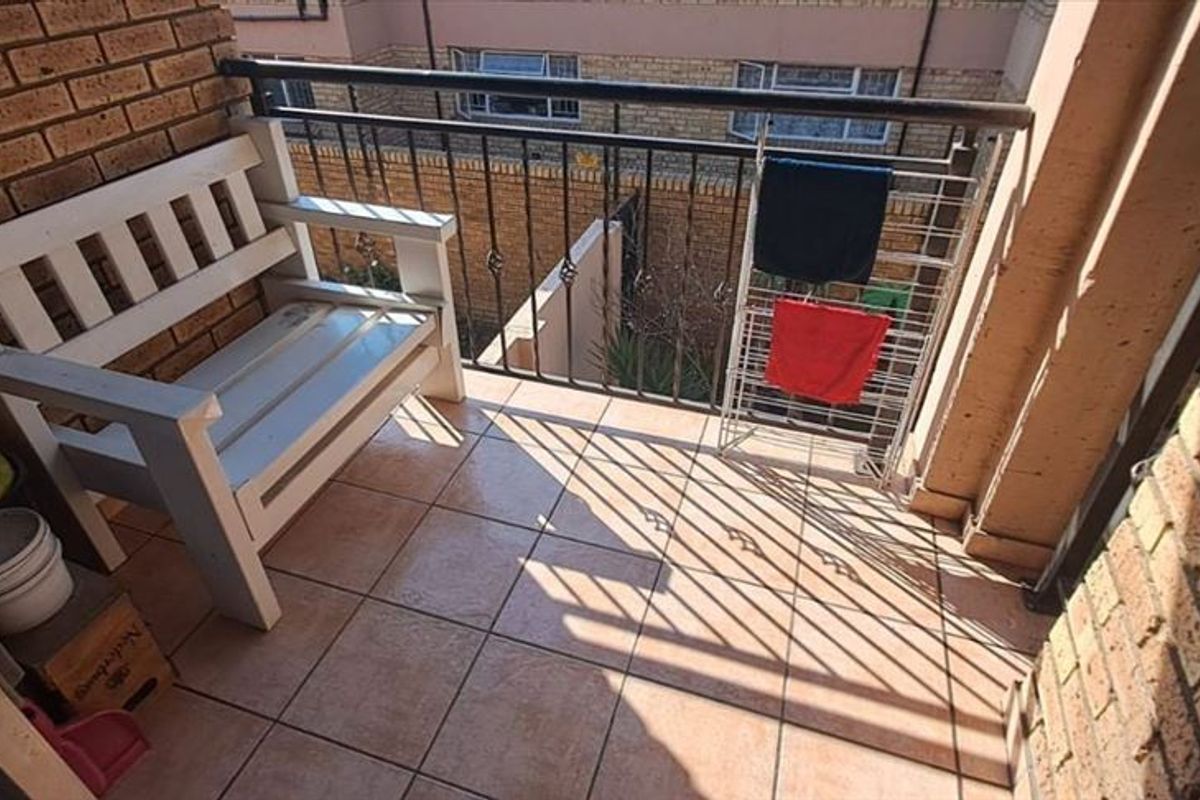 A compact balcony featuring tiled flooring, brick walls, and a metal balustrade, providing an outdoor space for relaxation.