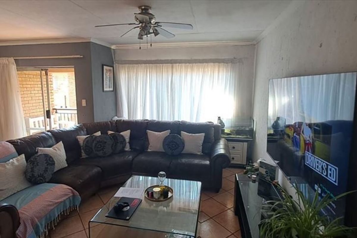 A comfortable living room featuring tiled flooring, a ceiling fan, and direct access to an outdoor patio area through sliding glass doors.