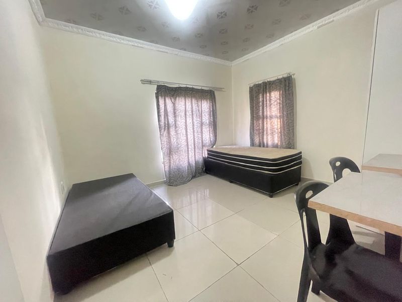 A bedroom featuring tiled flooring and ceiling cornice, currently showing signs of wear and requiring maintenance to the ceiling finishes.