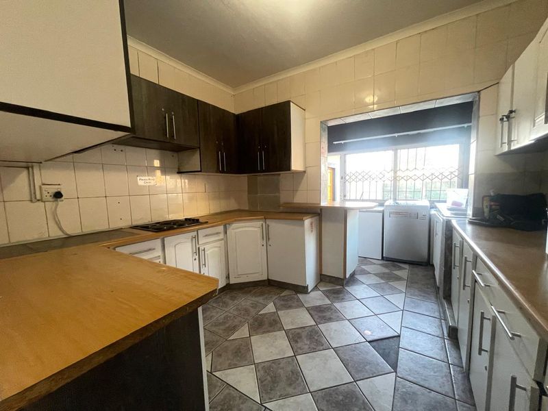 A functional kitchen featuring built-in cabinetry, laminate countertops, tiled backsplash, and ceramic flooring, offering potential for modernization and cosmetic updates.