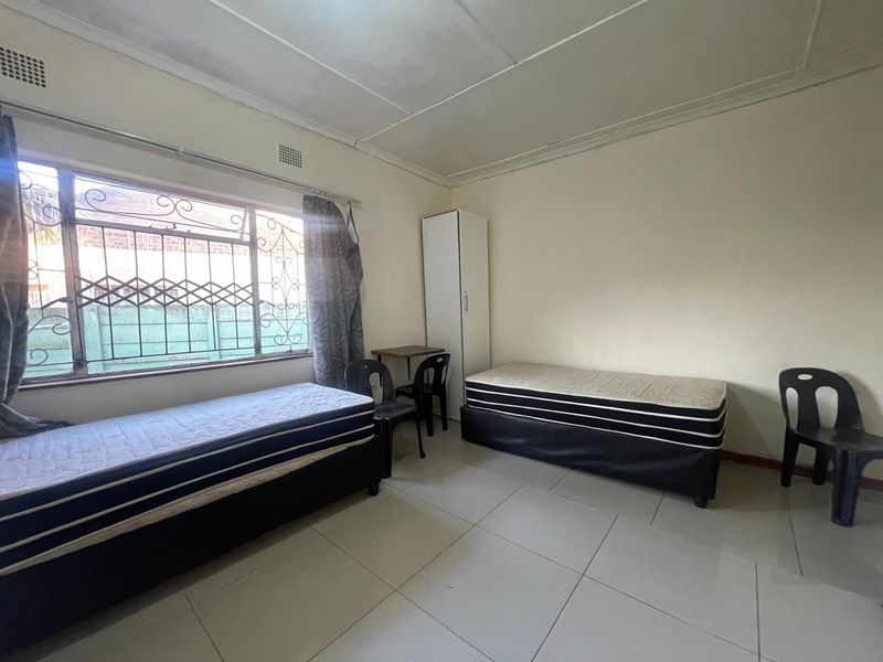A bedroom featuring tiled flooring, security bars on the window, and a built-in wardrobe, requiring some cosmetic updates to the ceiling and walls.