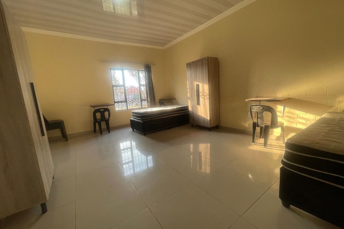 A spacious bedroom featuring tiled flooring, coved ceilings, and windows fitted with security bars, offering a functional and well-lit living space.