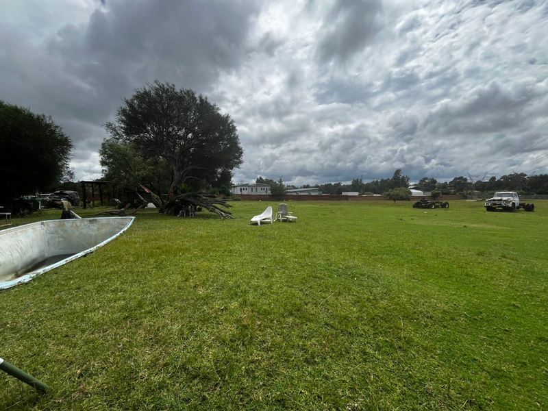 A large, open grass garden area featuring a mature tree and perimeter wall, providing significant outdoor space.