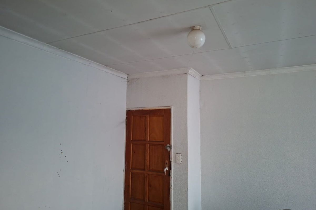 An empty room featuring a timber door, ceiling tiles, and coving, requiring cosmetic updates to improve the overall condition and appeal.