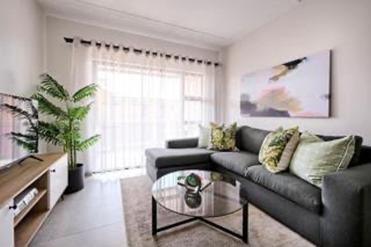 A bright and well-maintained living room featuring tiled flooring and a large sliding glass door that provides ample natural light.