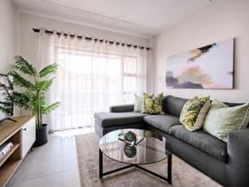 A bright and well-maintained living room featuring tiled flooring and a large sliding glass door that provides ample natural light.