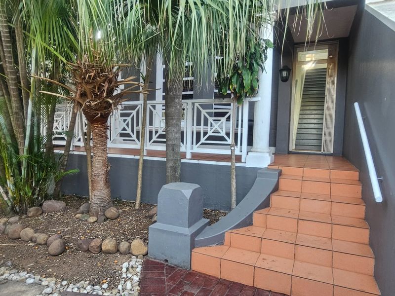 Front entrance featuring a tiled staircase with a handrail leading to a covered porch area with decorative balustrades.