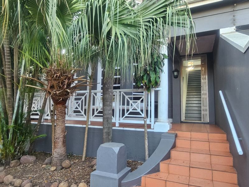 Front entrance featuring a tiled staircase with a handrail, leading to a covered porch area with decorative balustrading and a secure entry door.
