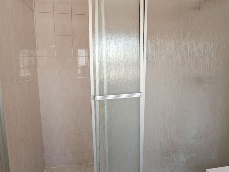 A functional shower area featuring tiled walls and a standard framed shower enclosure, ready for modernization.