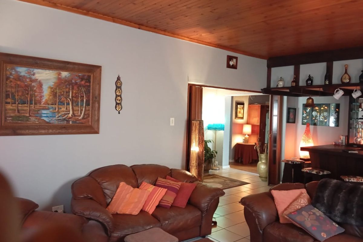 Spacious living room featuring a warm timber ceiling, tiled flooring, and an integrated built-in bar area, creating a cozy and inviting atmosphere.