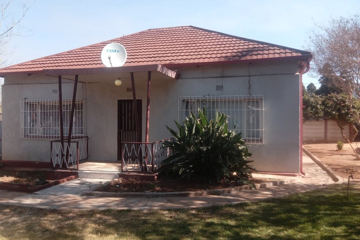 Front elevation of a single-story house featuring a tiled roof, covered porch area, and security bars on windows.