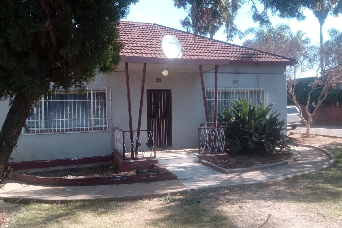 Front elevation of a single-story house featuring a tiled roof, covered entrance porch, and security bars on windows.
