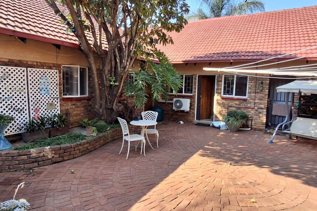 A private rear courtyard featuring brick paving, a raised planter bed, and direct access to the main dwelling with an installed air conditioning unit.