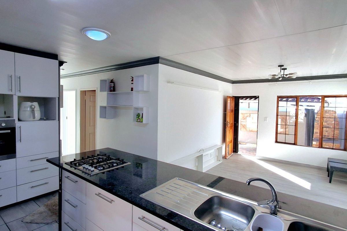 Open-plan living area featuring a modern kitchen with a gas hob, built-in oven, granite countertops, and seamless flow to the adjacent living space.
